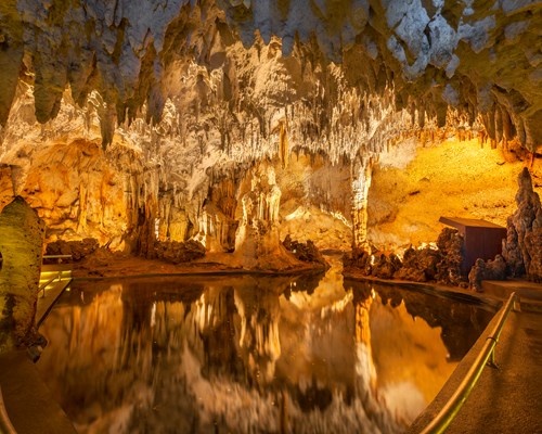Inside of an old cave with a ceiling covered in stalactites hanging down