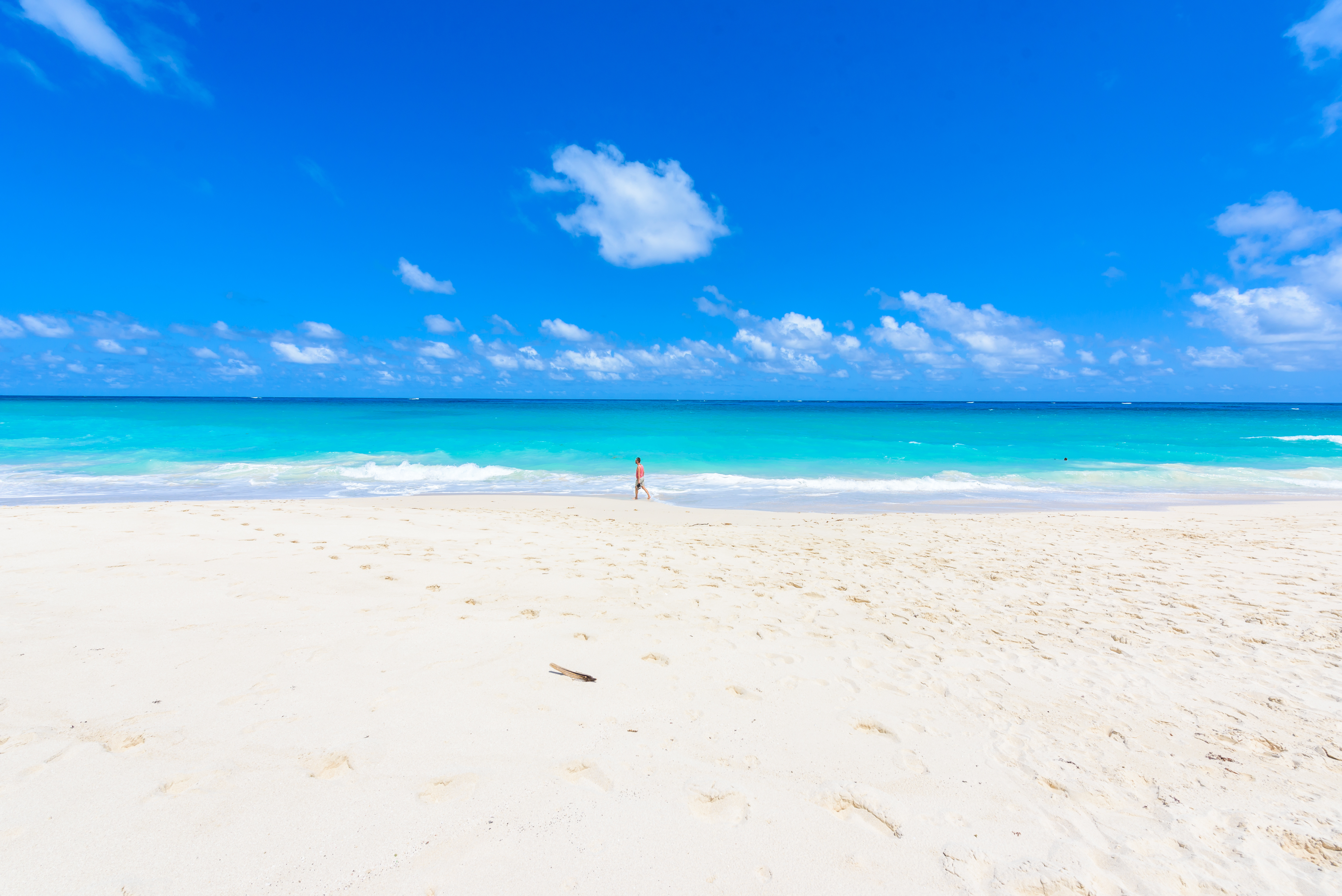 Man walking along a pristine white tropical beach