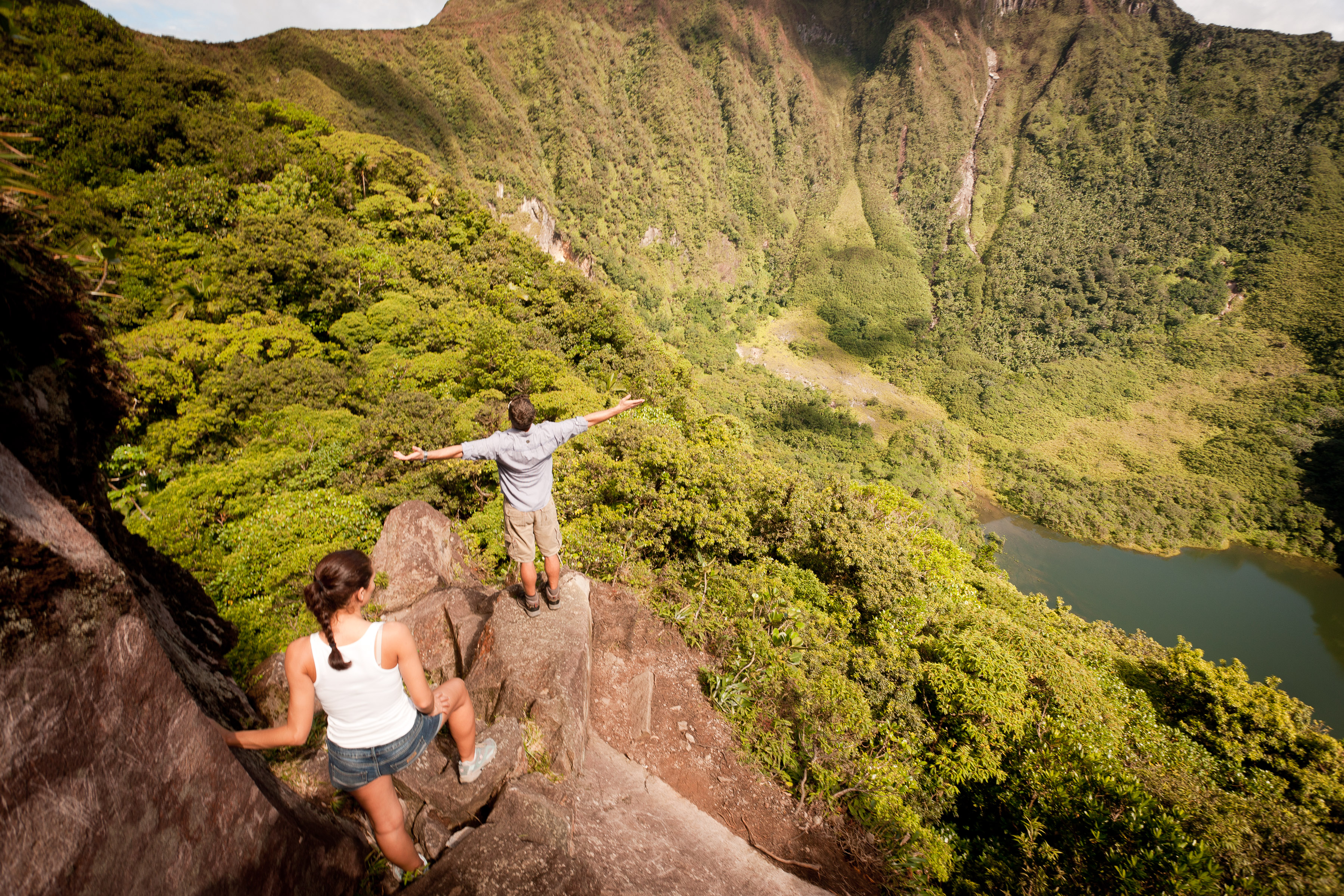 A couple hiking up a volcano covered in rainforest