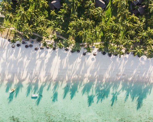 Aerial view of small blue boat docked by a white sand tropical beach