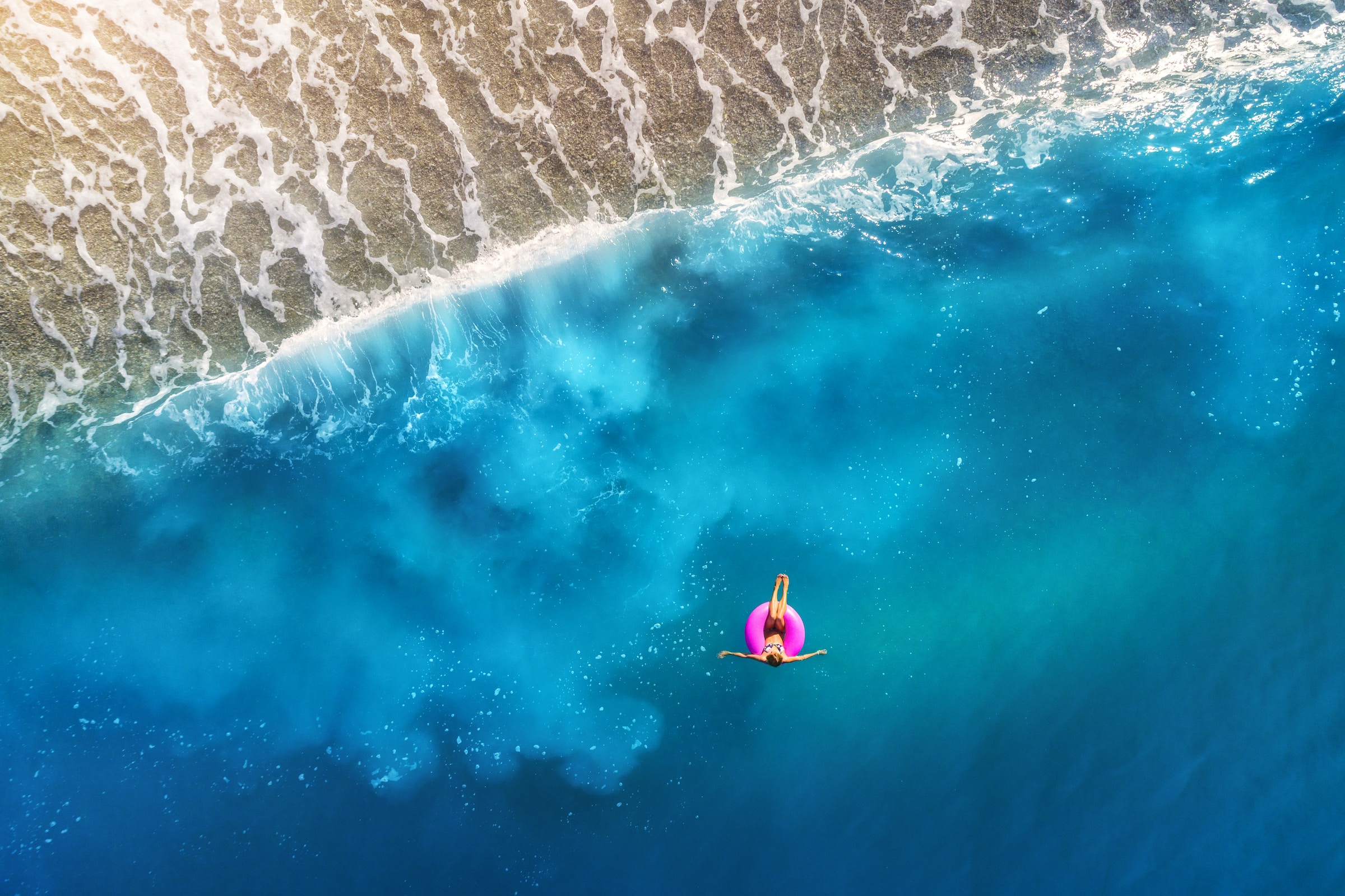 A woman paddling in a pink float in the middle of the sea