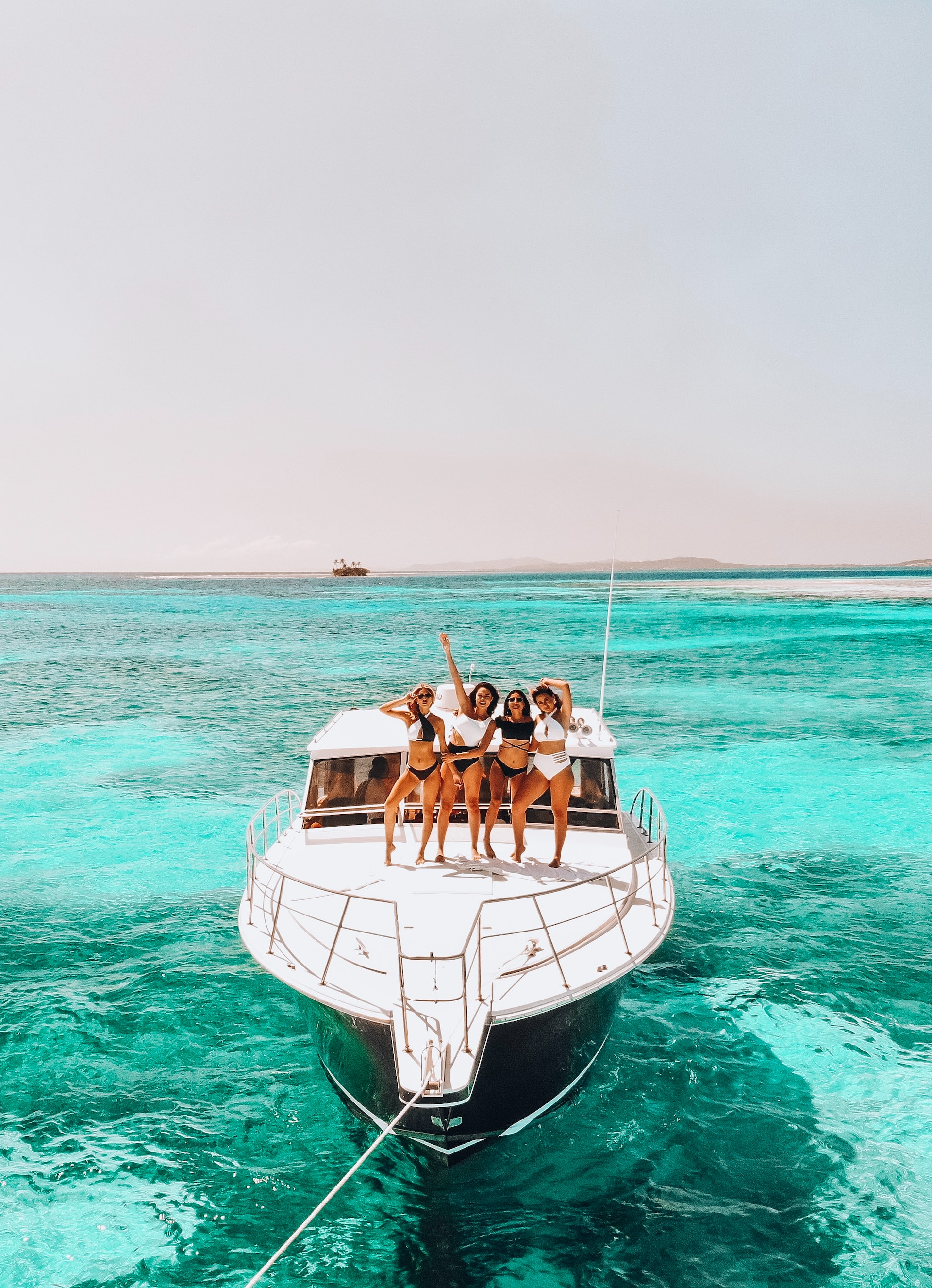 Four girls standing on a white boat in the middle of the ocean