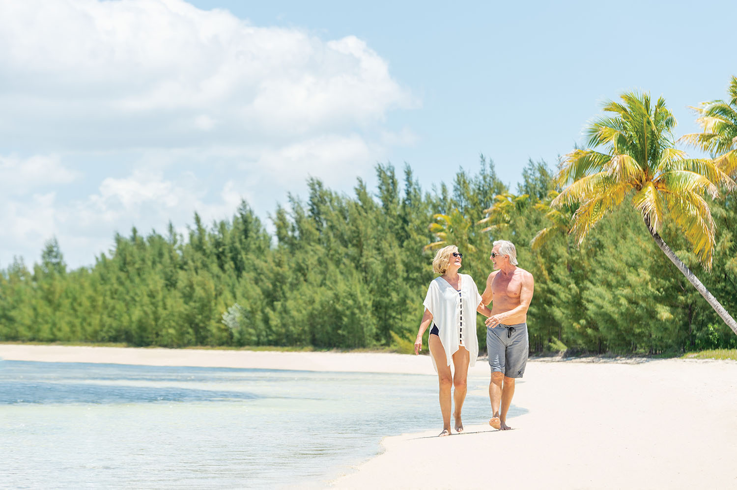 Older couple walking along tropical beach