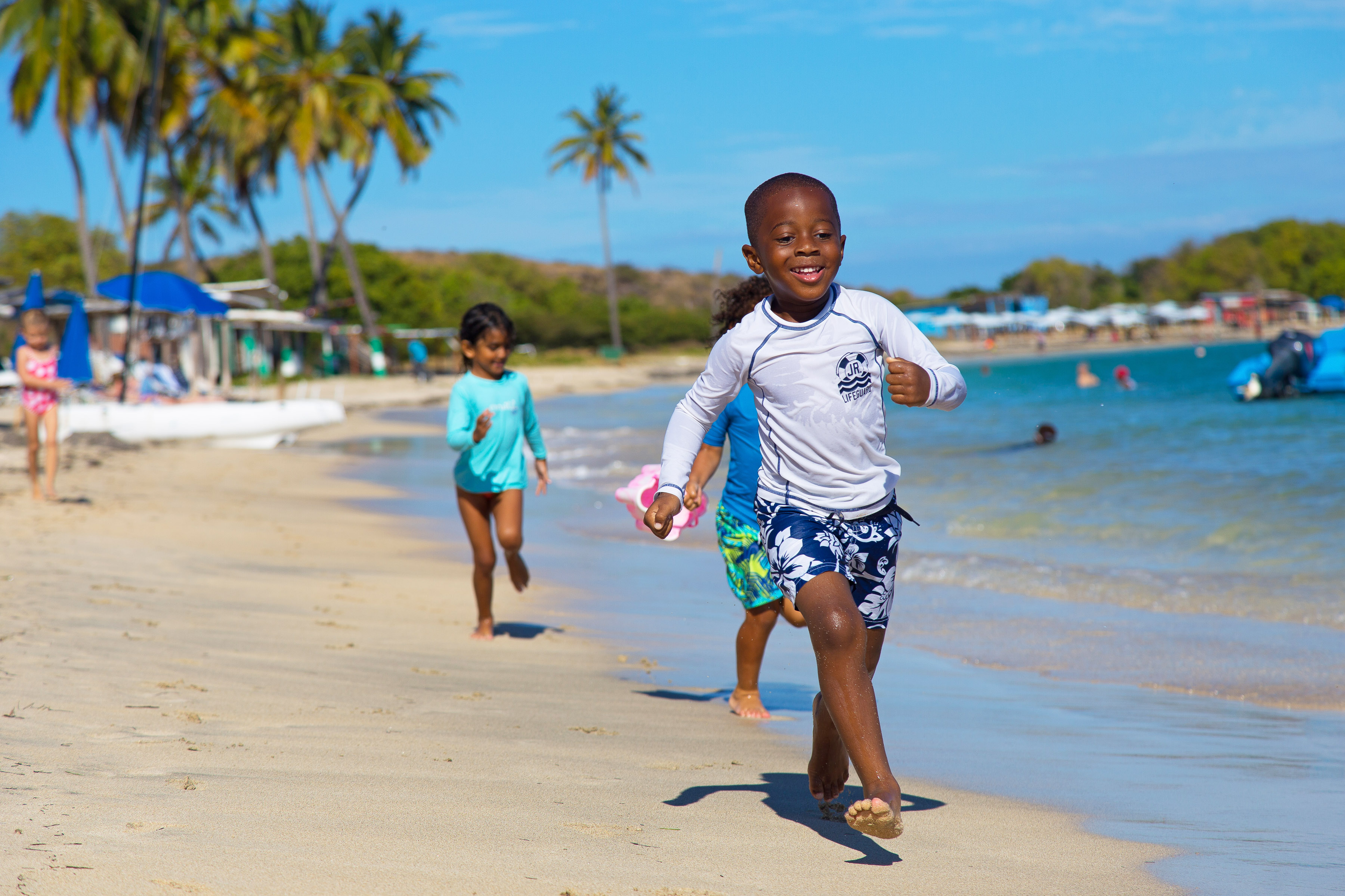 Happy kids running across a tropical beach