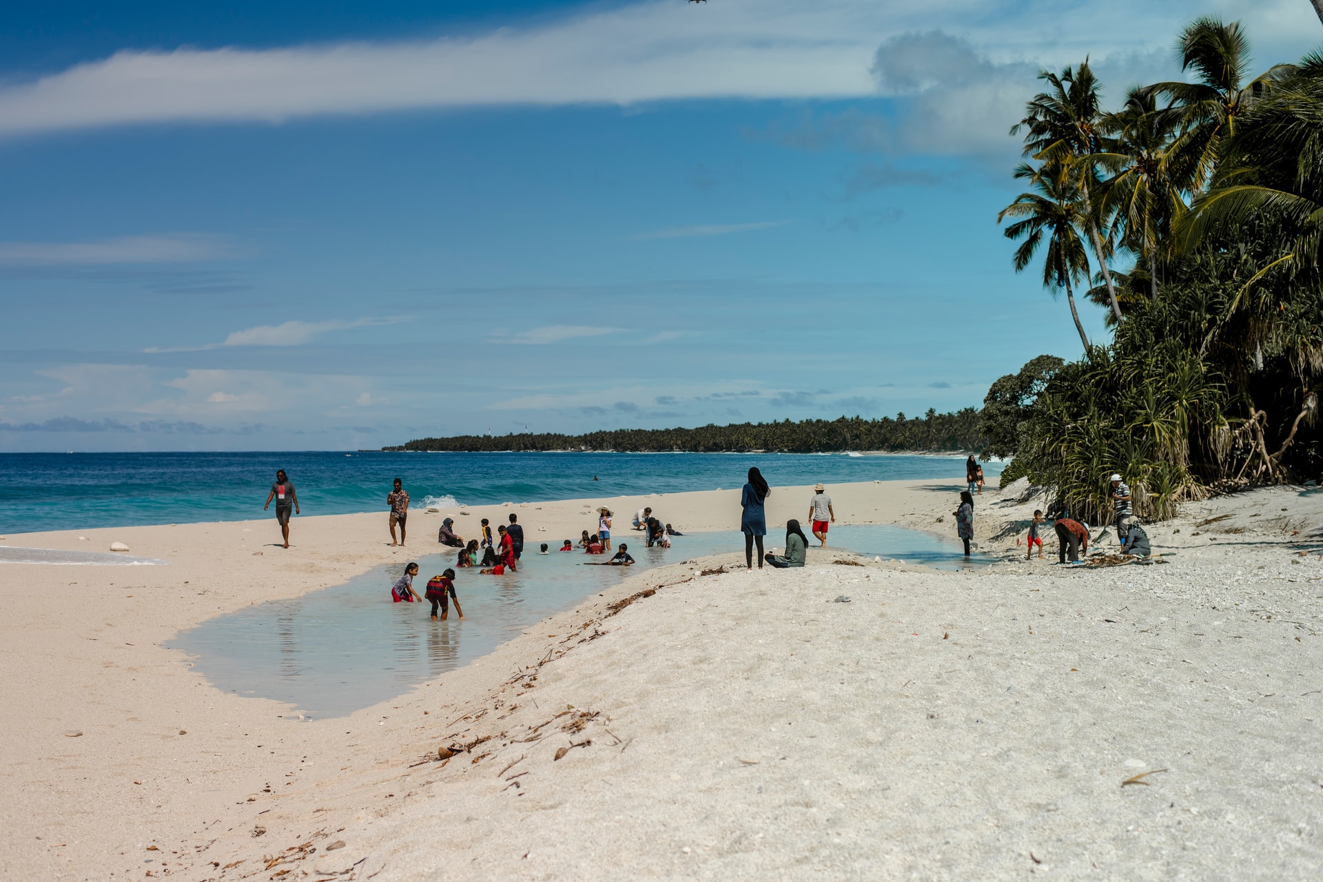 People enjoying a shallow lagoon on a powdery white beach