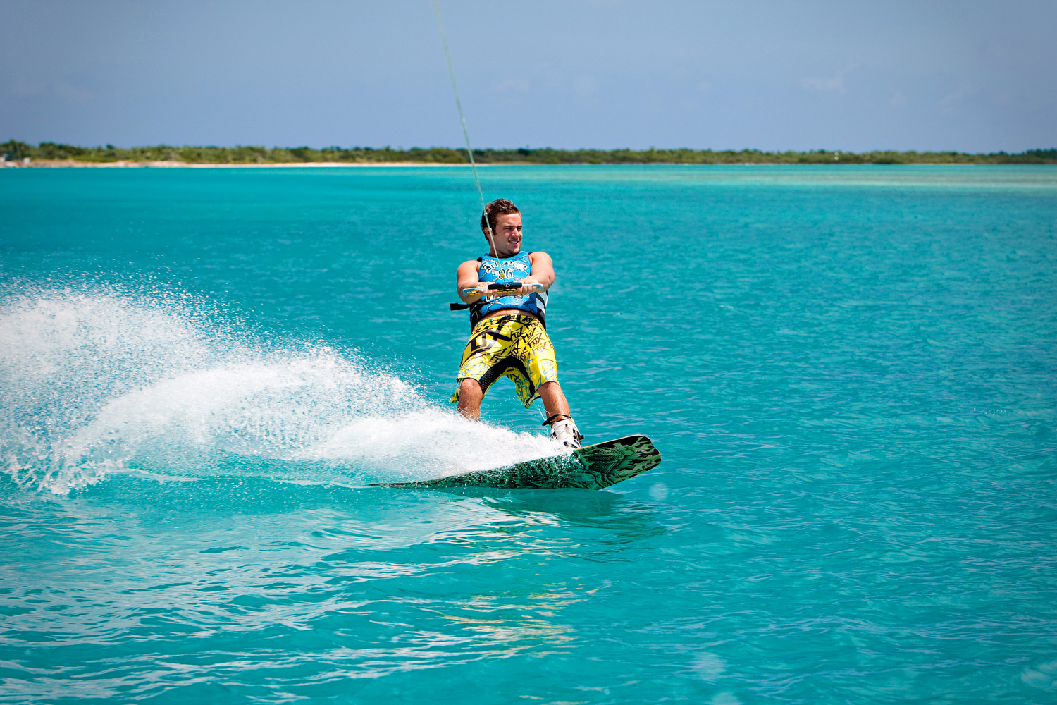 Man wakeboarding on a bright blue sea in a tropical destination