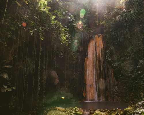 Tall waterfall cascading through a cave and into a pool of water