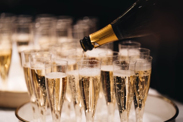 Full glasses of champagne on a tray with a bottle pouring champagne into a glass 