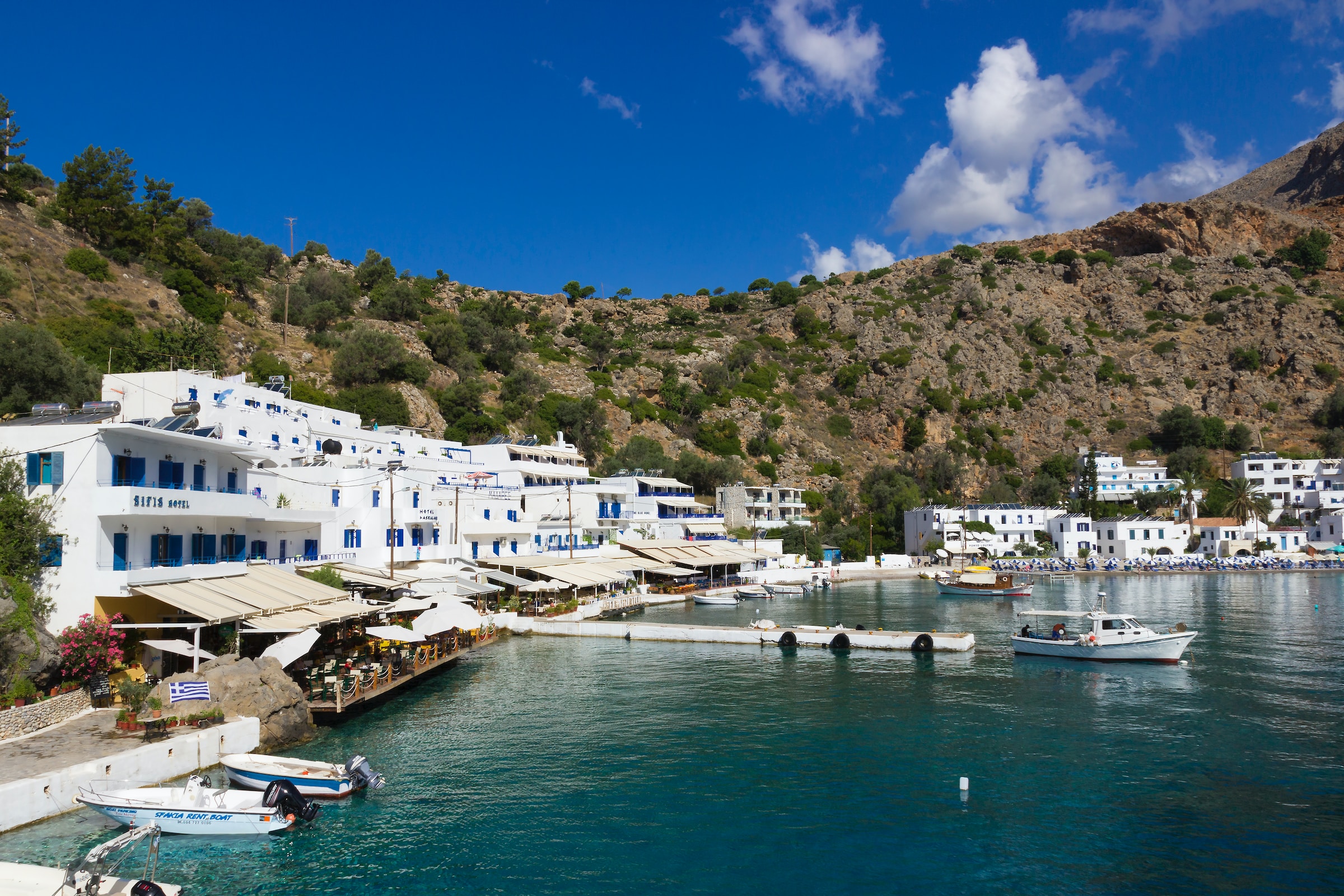 A small cove with bobbing boats encompassed by white buildings
