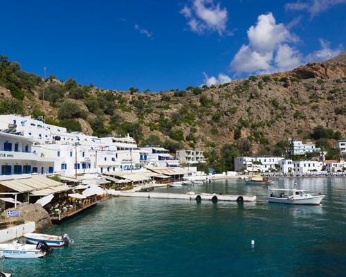 A small cove with bobbing boats encompassed by white buildings