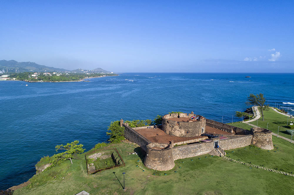 A fort on a hill overlooking a bright blue sea