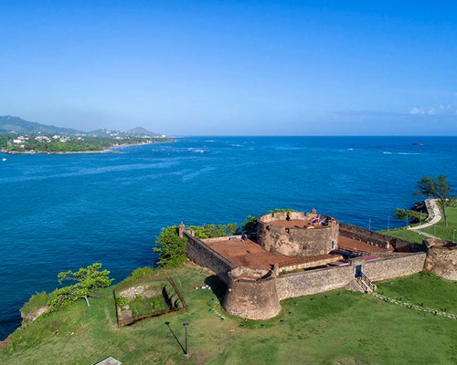 A fort on a hill overlooking a bright blue sea