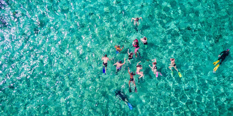 Aerial view of people snorkelling in tropical blue sea