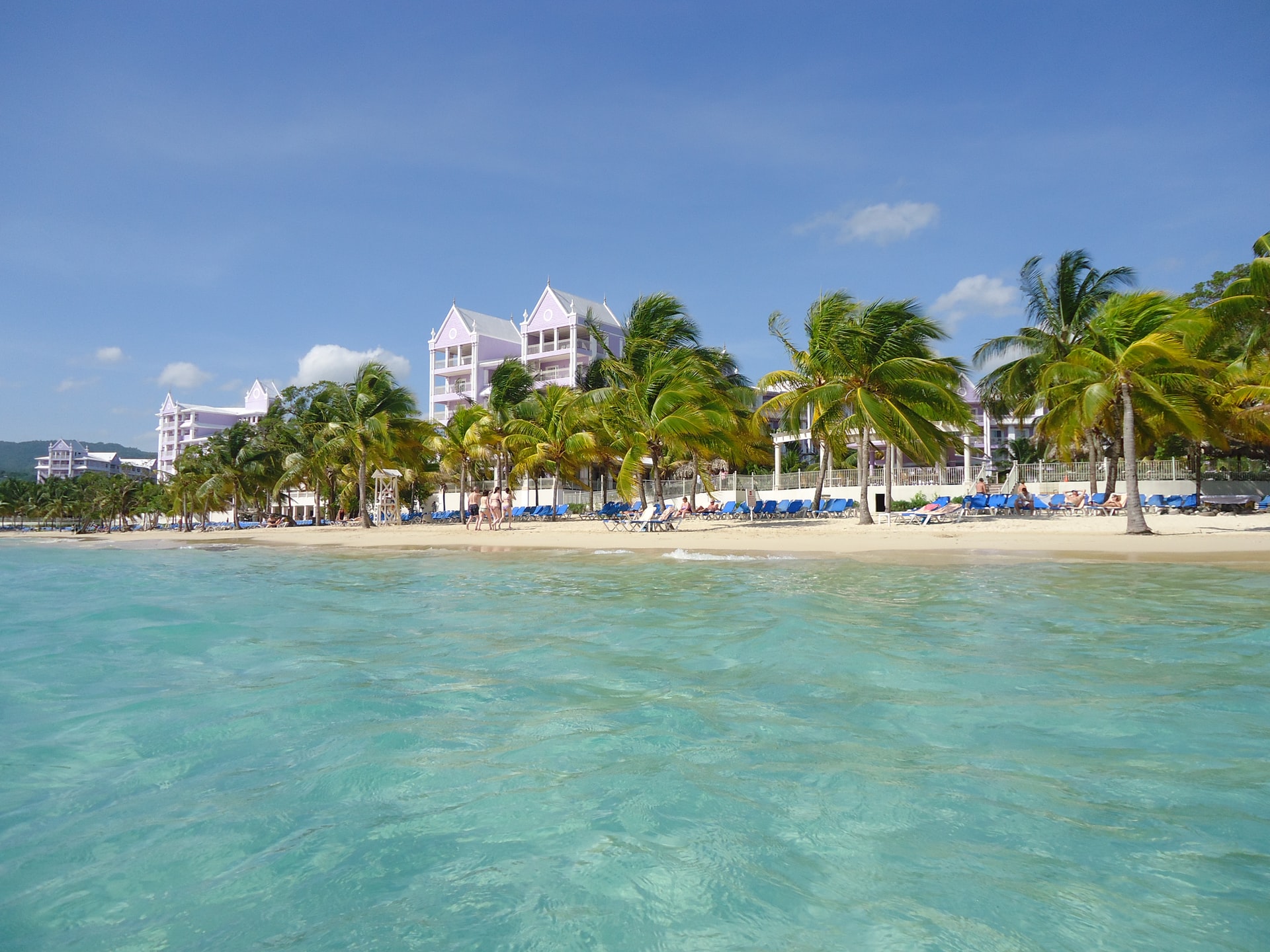 Sunloungers lined up on a narrow white sand beach in a Caribbean destination