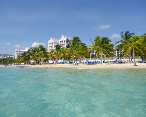 Sunloungers lined up on a narrow white sand beach in a Caribbean destination