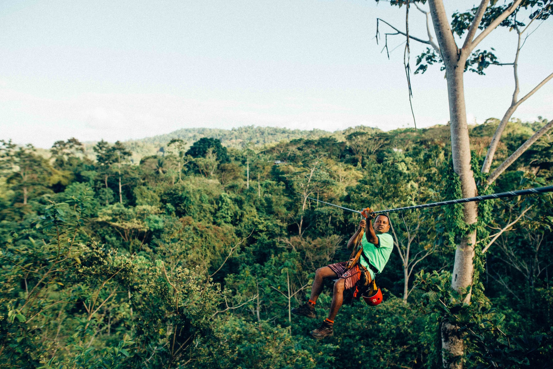 Man zip-lining through rainforest 