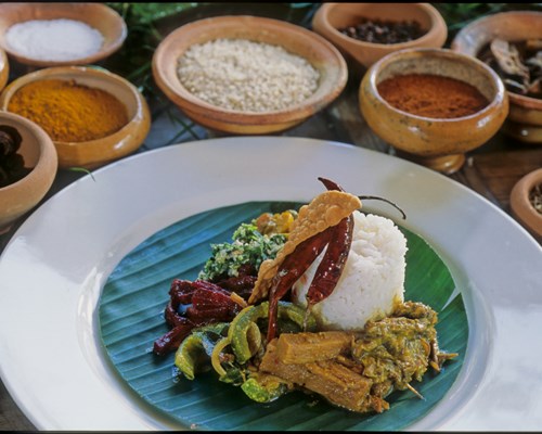 Gourmet food on blue and white dish with ceramic bowels of spices around the edge - Colombo