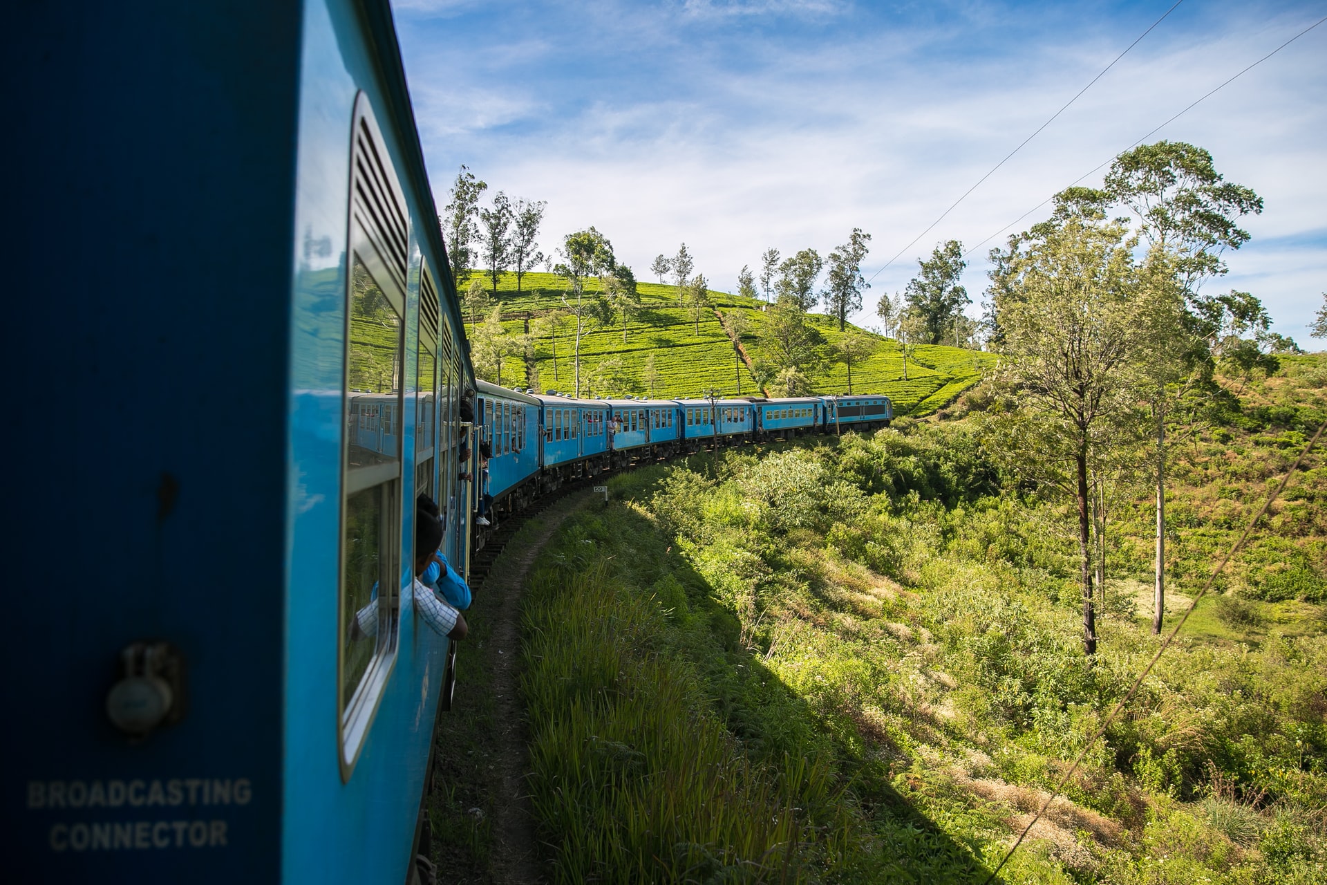 Blue train travelling over a hill in Sri Lanka countryside