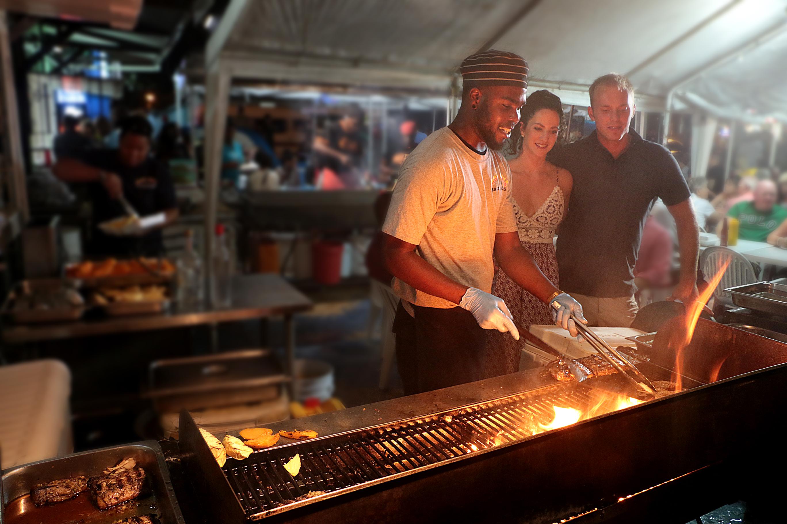 Couple watching a bbq chef at Oistins Fish Fry