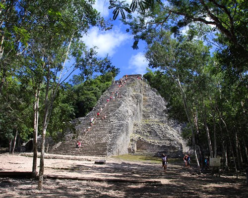 People walking up stone steps on ruins of a pyramid