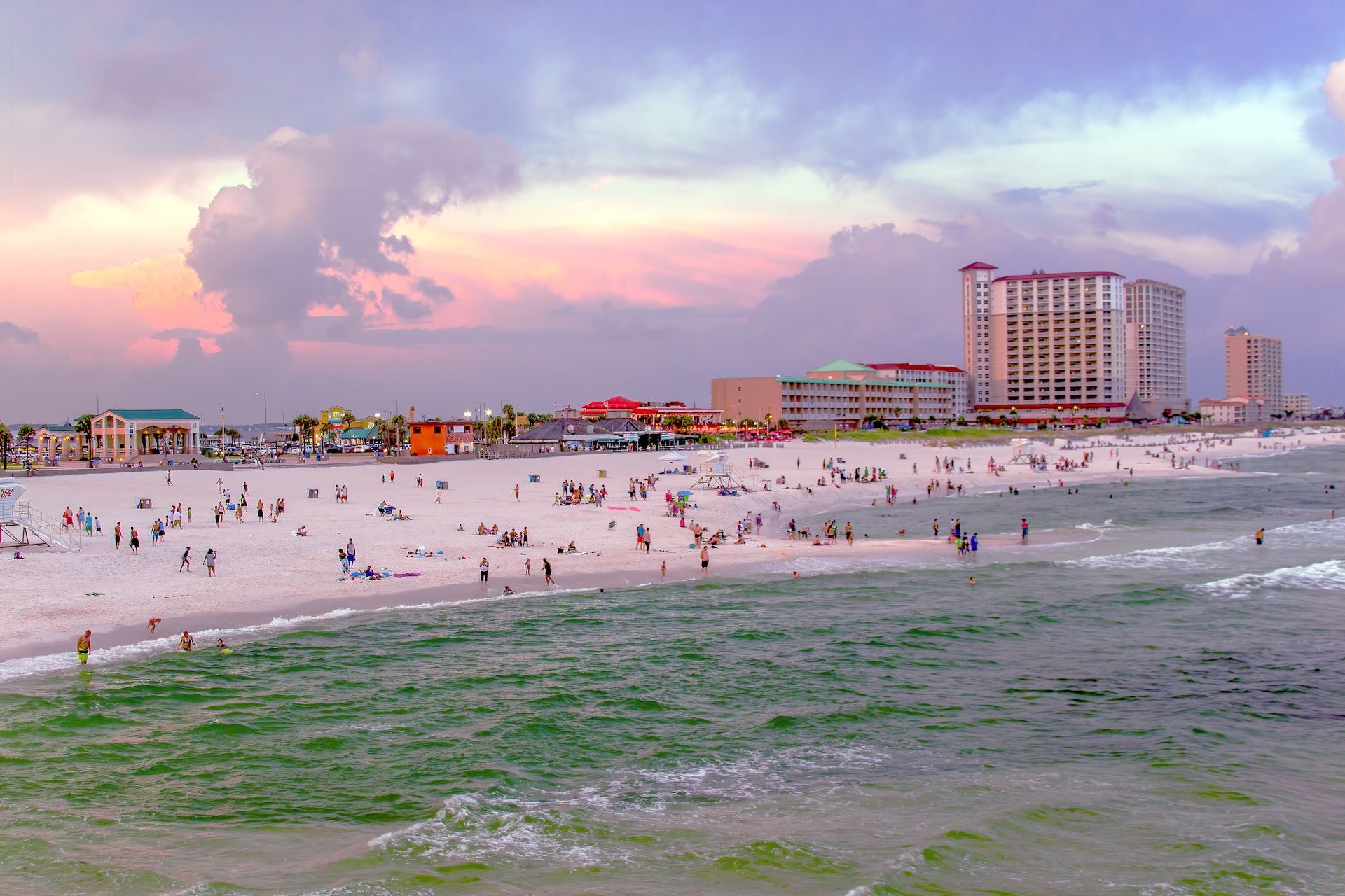 Crowds of people on Pensacola Beach fringed by a handful of resorts