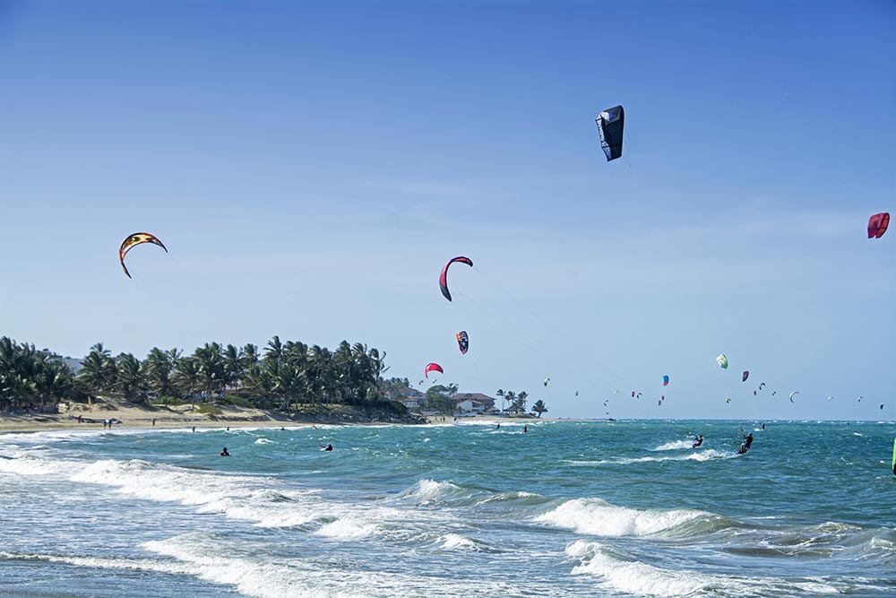 Lots of people kite surfing at a windy beach in the Caribbean 