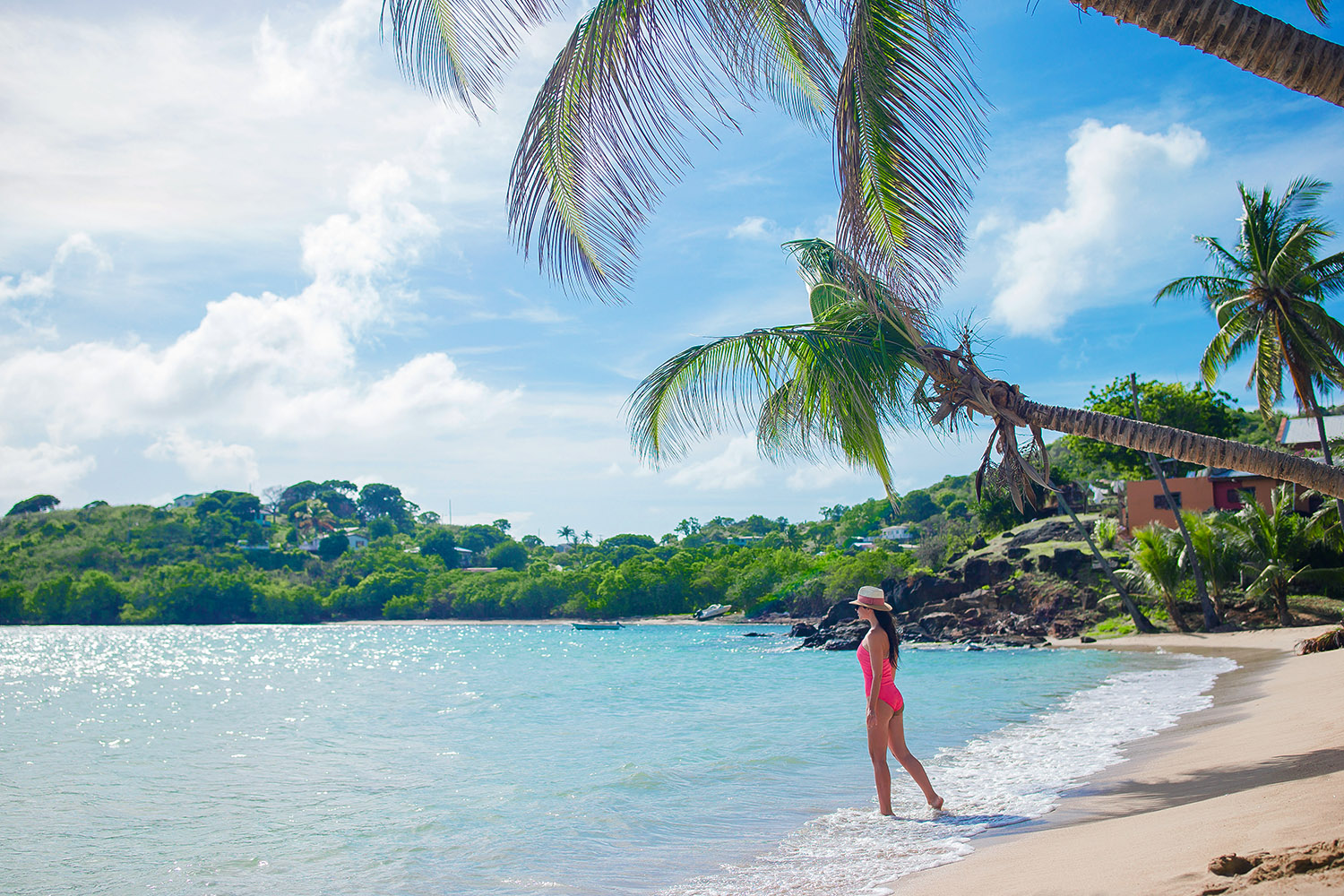 Woman in pink swimsuit walking along tropical beach
