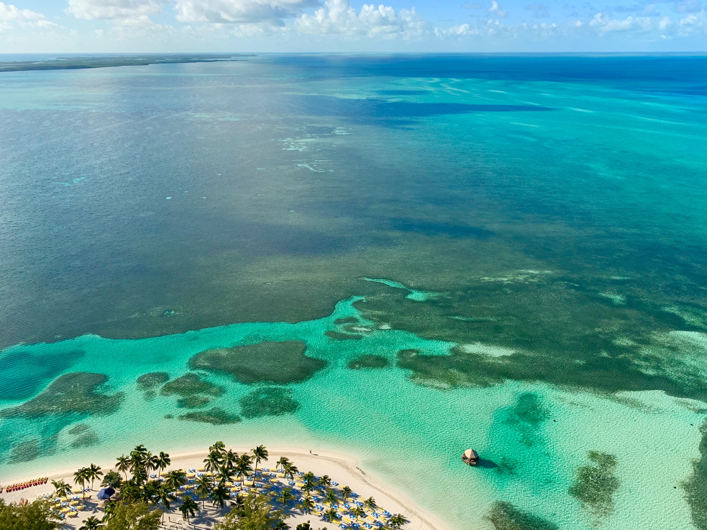 Aerial photo of an edge of a tropical white sand beach and clear turquoise sea