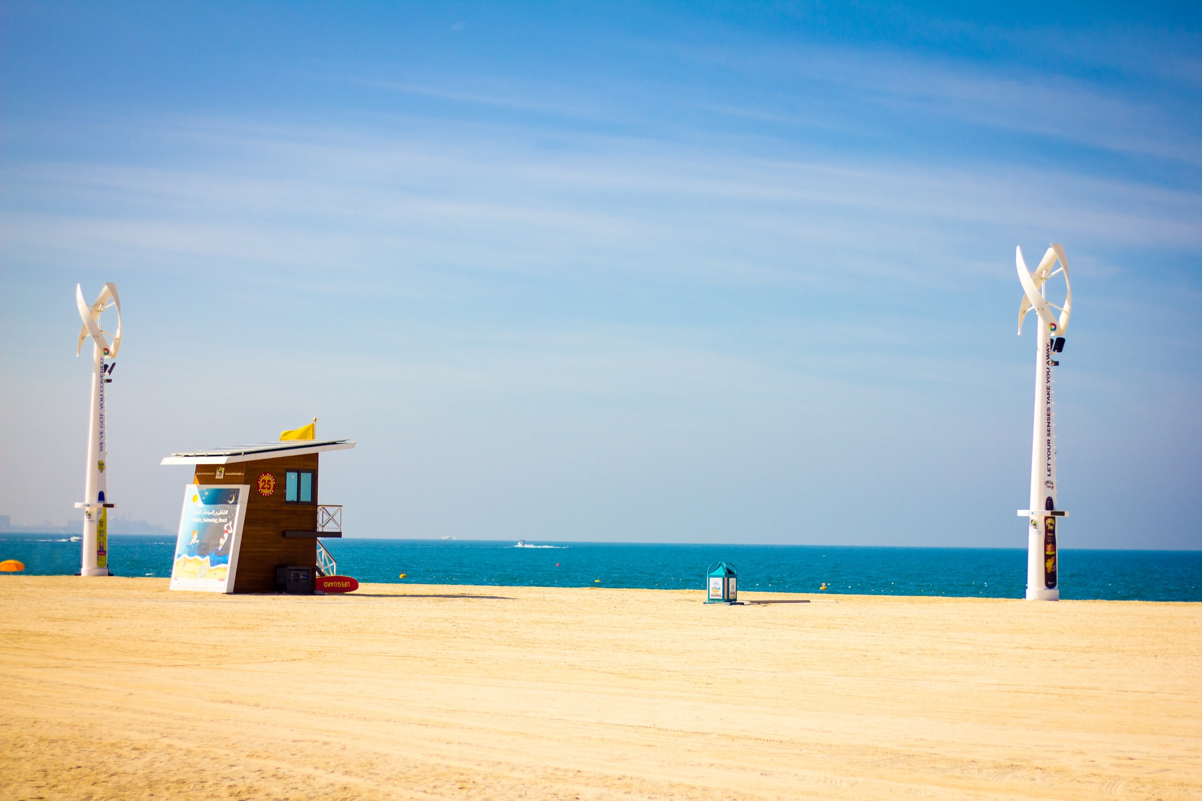 A small beach shack and turbines on a golden beach in Dubai