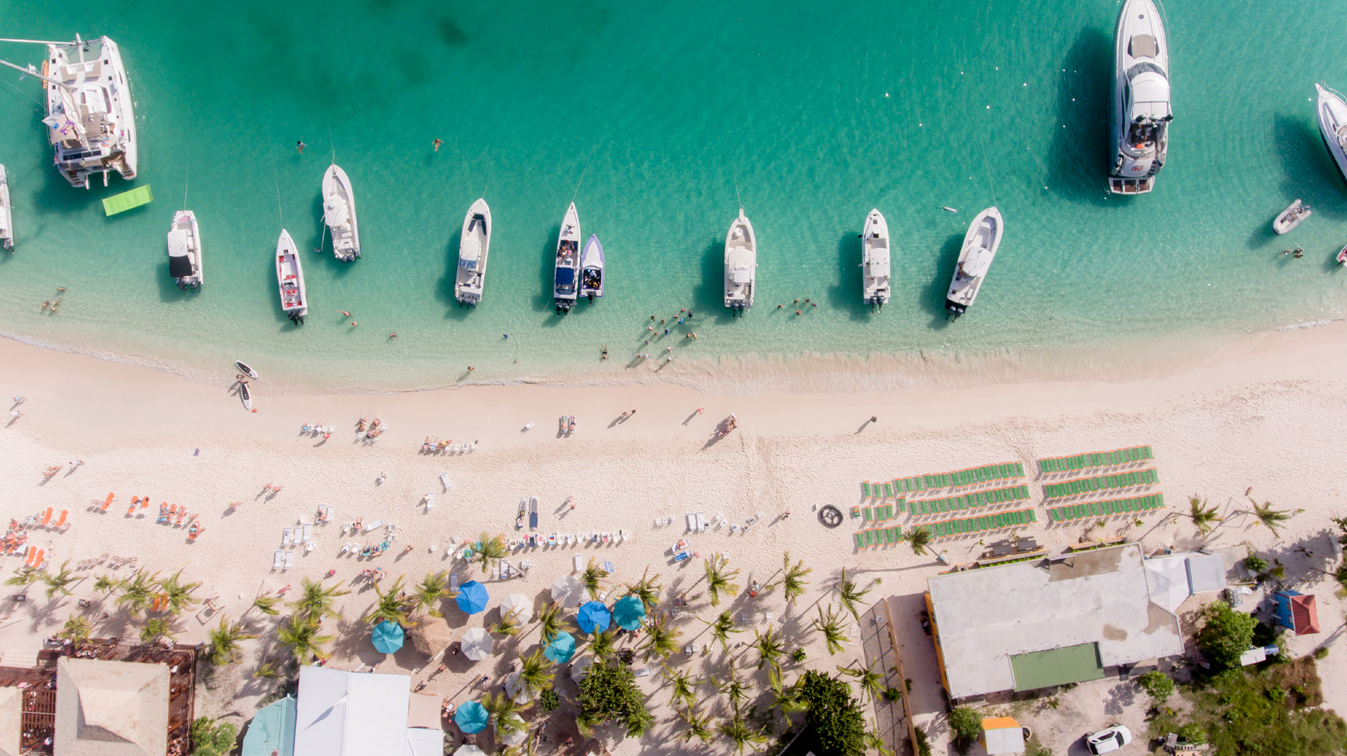 Yachts anchored on busy white sand beach in BVI - White Bay