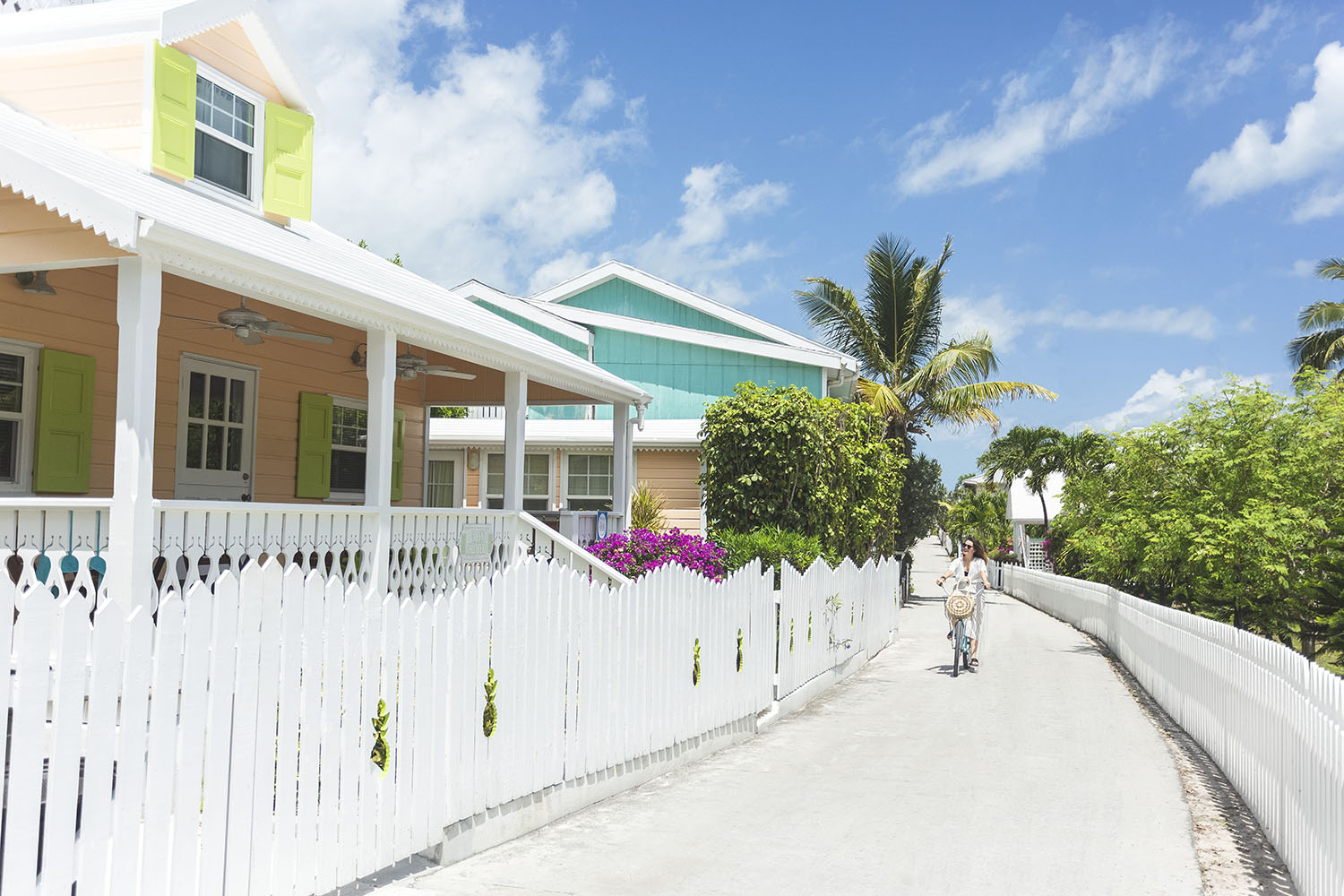 Woman riding bicycle past colourful houses in The Bahamas