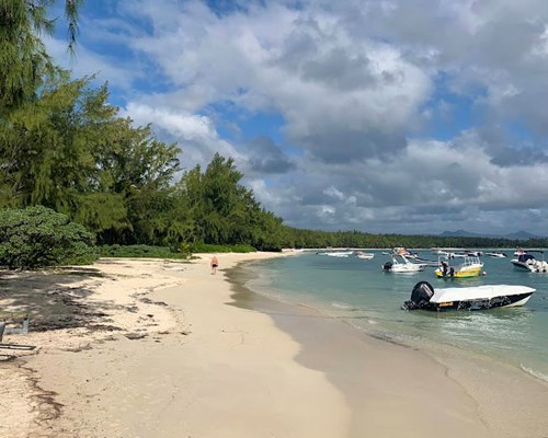 Man walking along curved white sand tropical beach