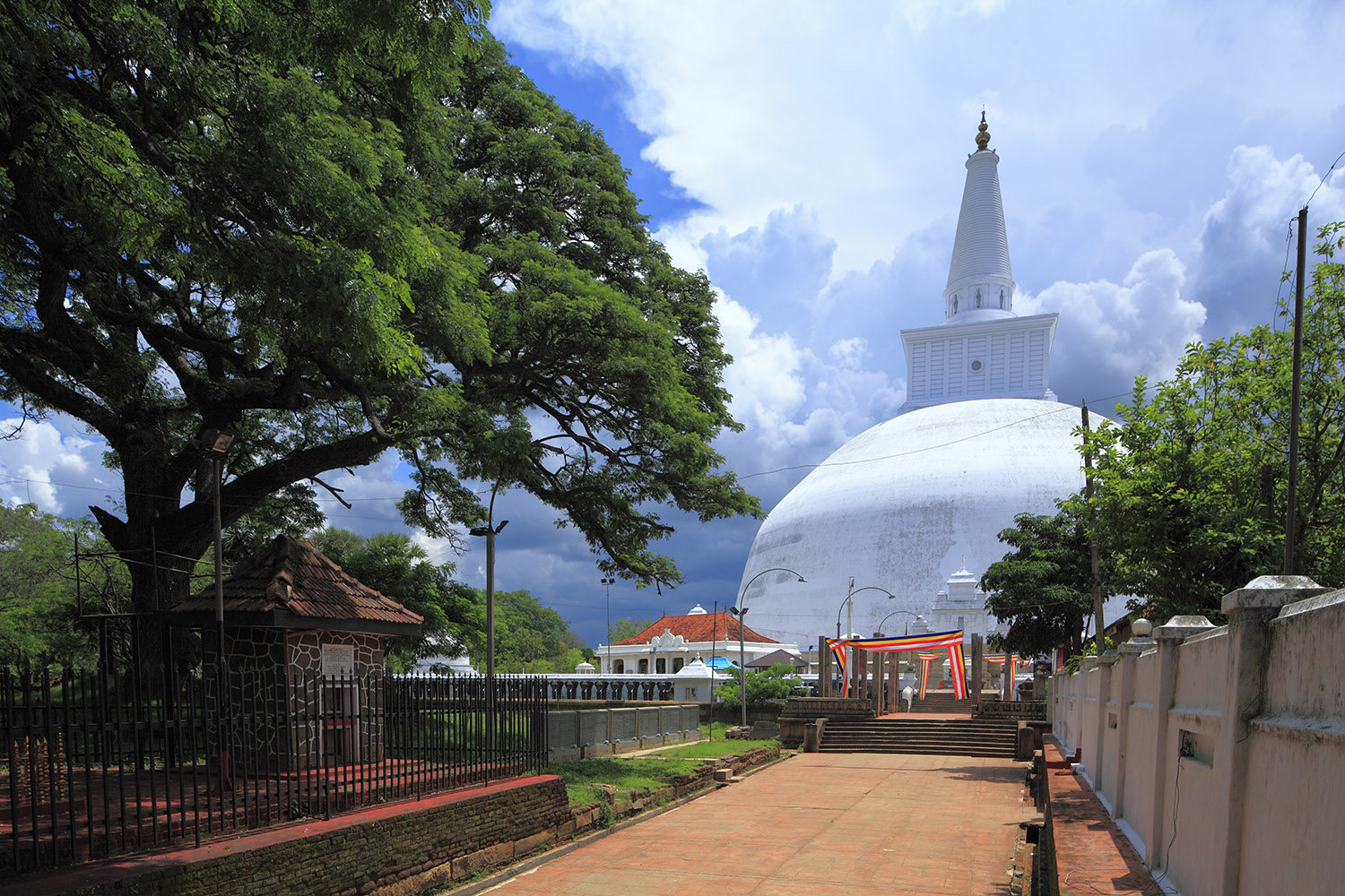 White hemispherical shaped temple surrounded by trees and stone walls