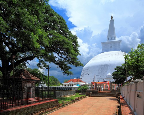 White hemispherical shaped temple surrounded by trees and stone walls