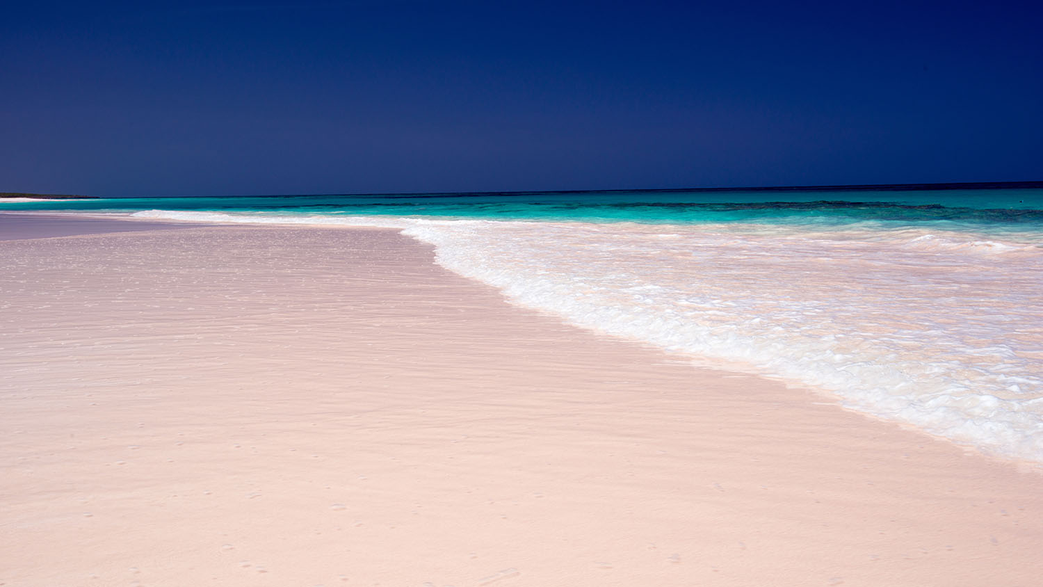 Waves crashing on a pink sand beach