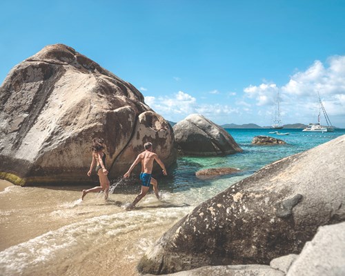 Man and woman running through boulders at The Baths - Virgin Gorda