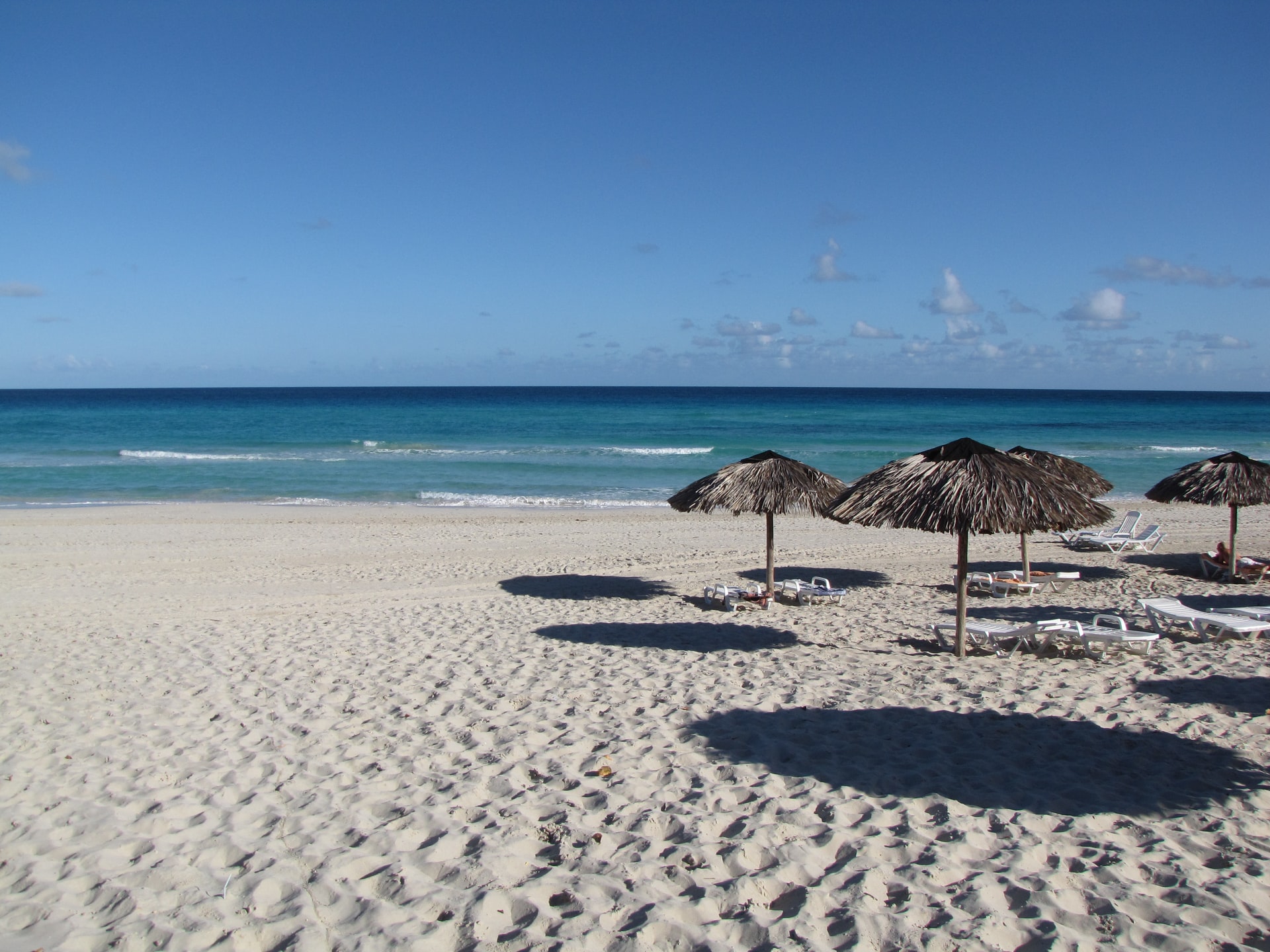Straw parasols and white sun loungers on a white sand beach