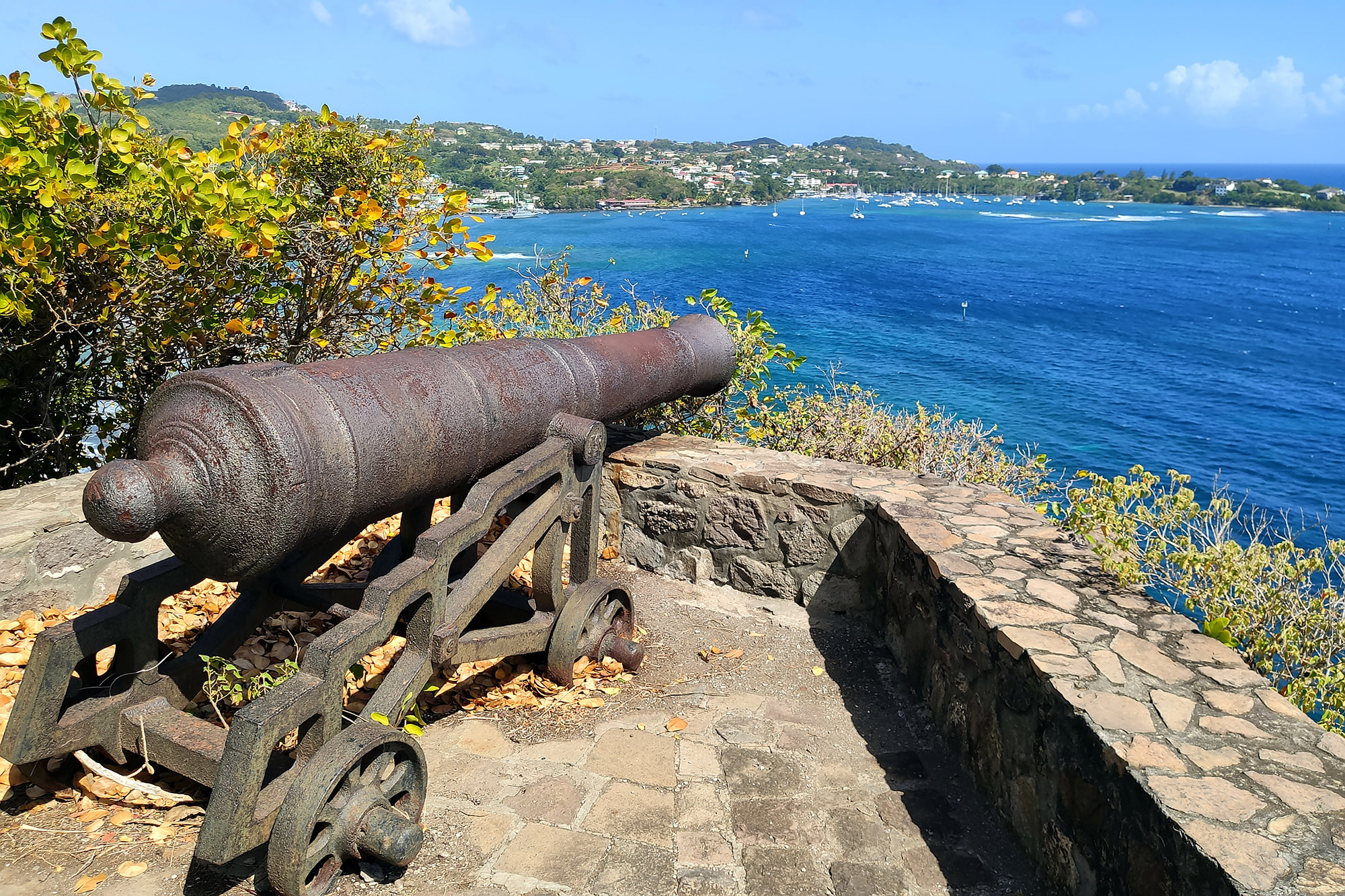 Old cannon on a cliff overlooking a bright blue sea