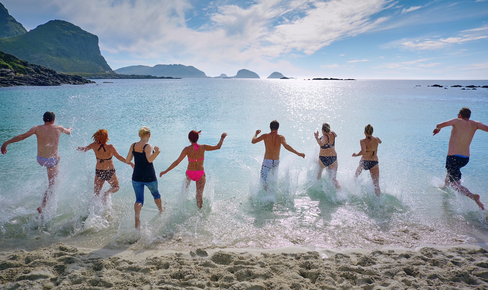 group running into sea from tropical beach