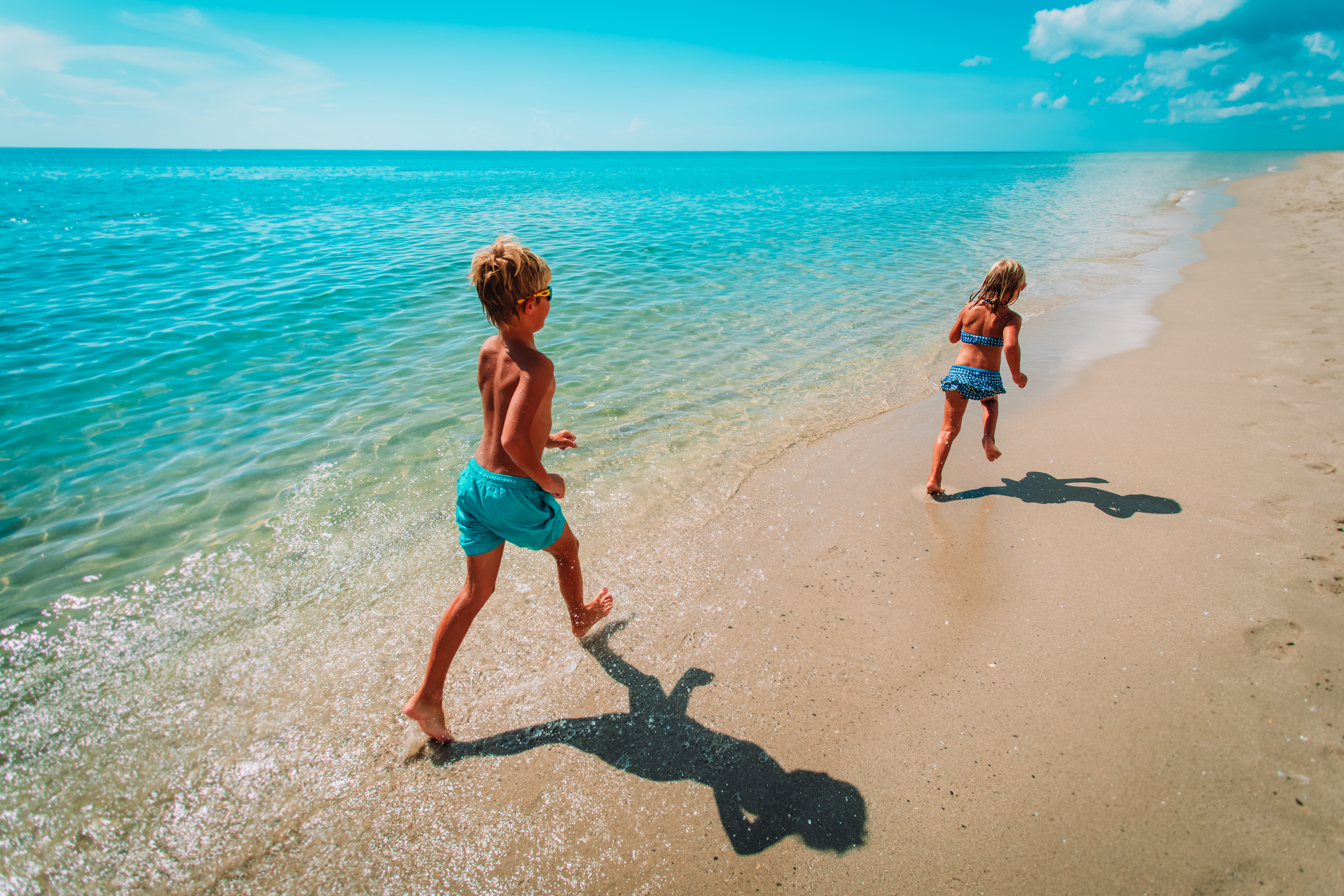 Happy young boy and girl running on a tropical beach 