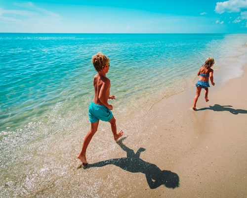 Happy young boy and girl running on a tropical beach