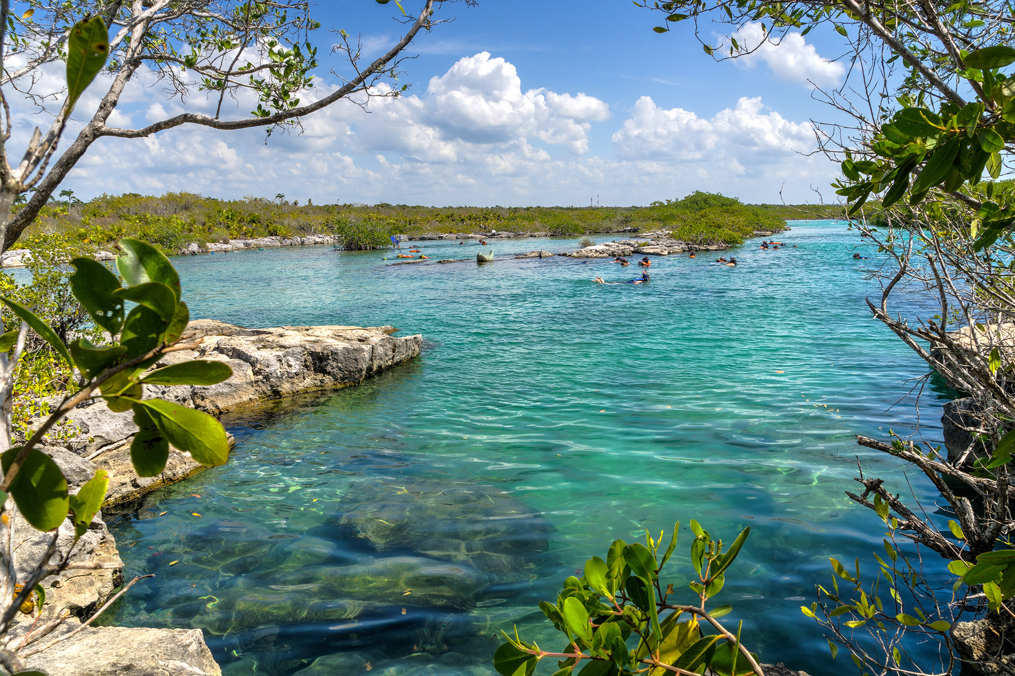 People swimming in large lagoon with clear turquoise water 