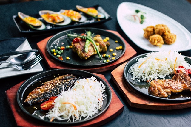 Selection of different foods on black plates and wooden boards 