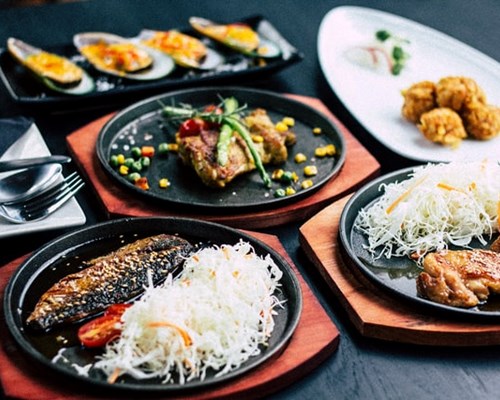 Selection of different foods on black plates and wooden boards