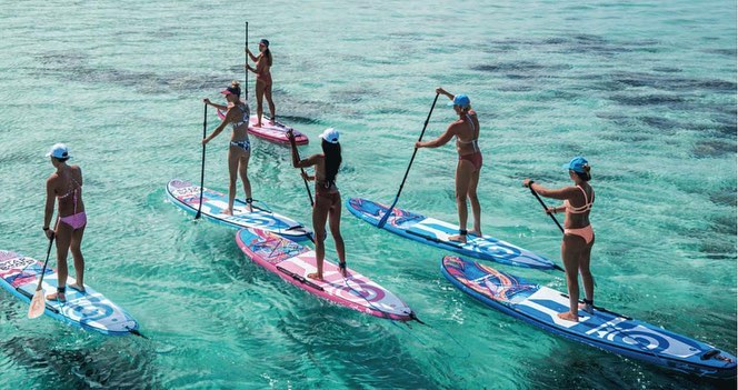 Six people paddle boarding in the blue sea