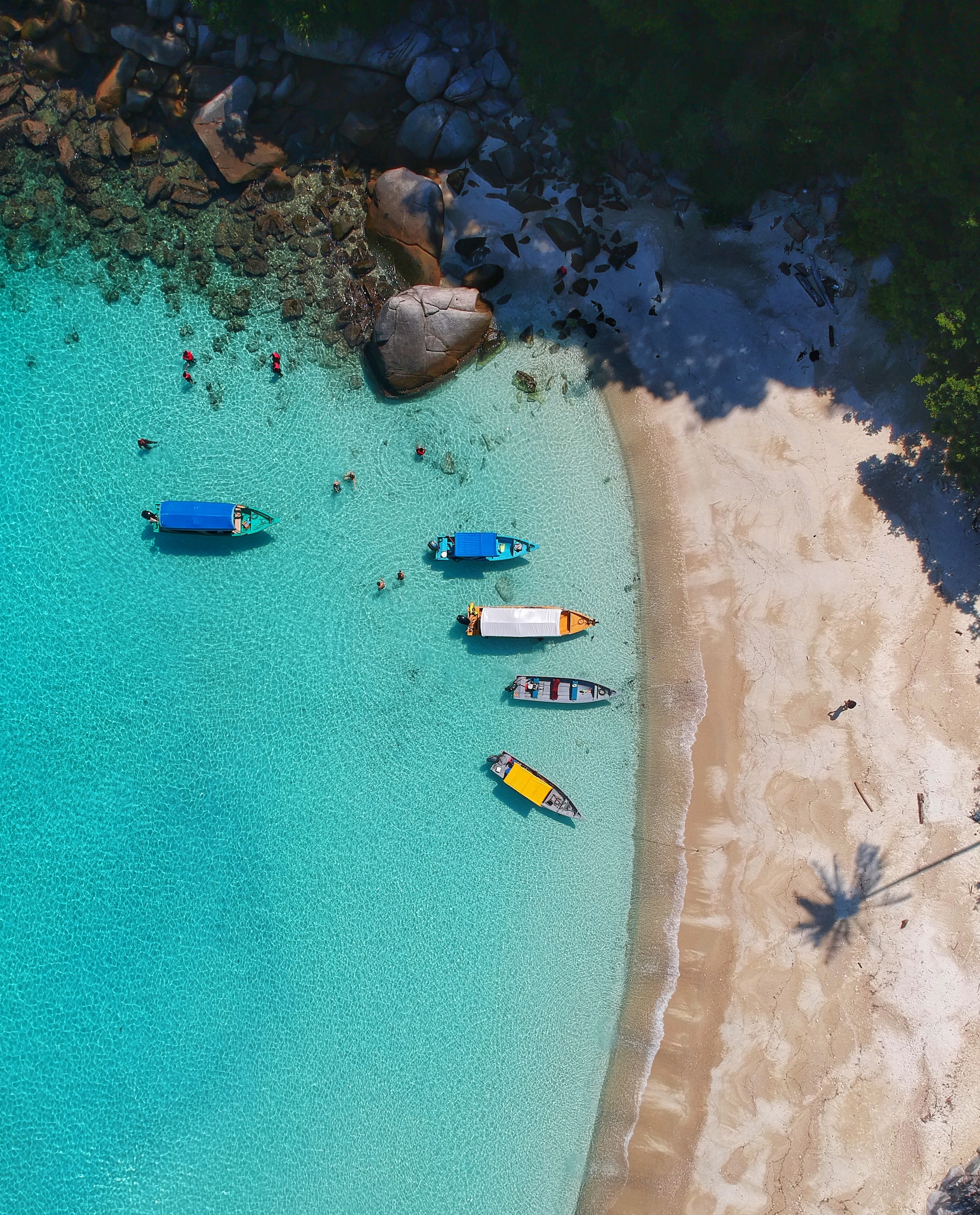 Boats docked onto a light blue beach