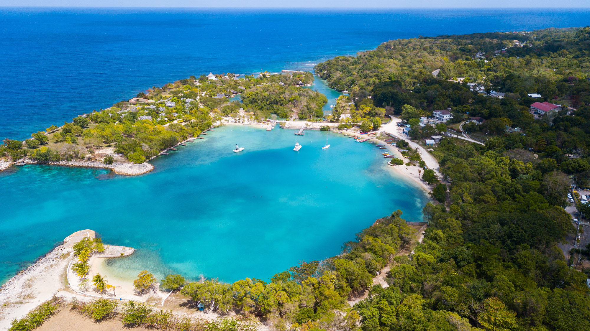 Aerial view of a cove with white sand beaches and bright blue water 