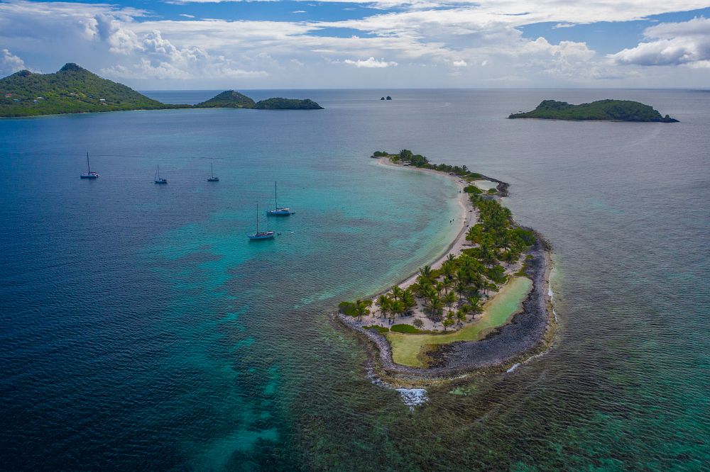 Yachts docked up in turquoise coloured sea around a small tropical island - San