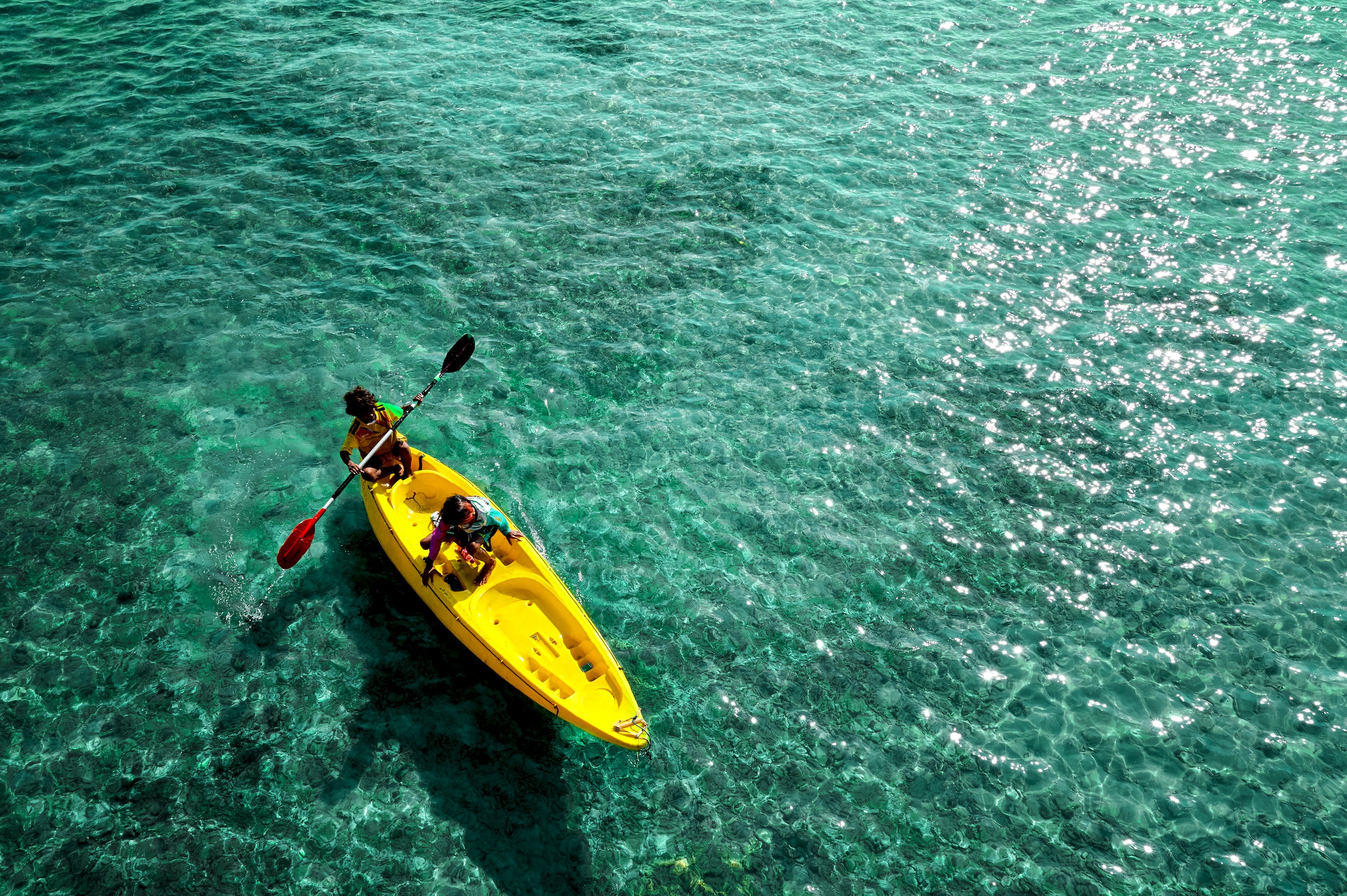 A man paddling on electric-blue waters