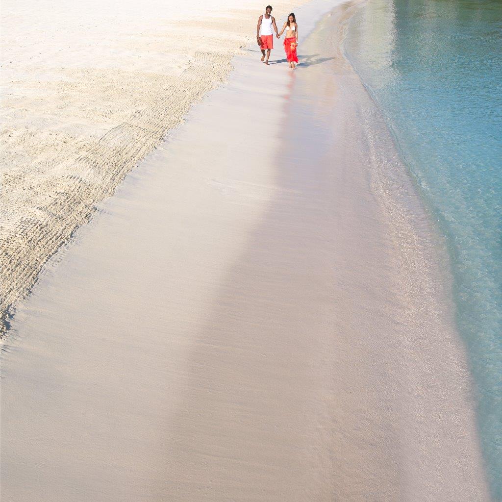 A couple walking along a white sand beach